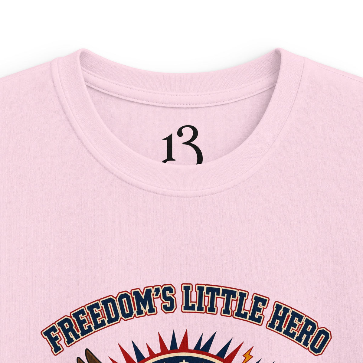 Close-up of light pink kids T-shirt neckline and “Freedom’s Little Hero” graphic.