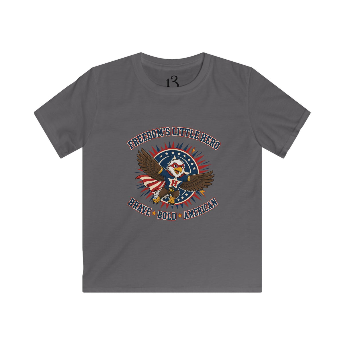 Front view of charcoal kids T-shirt with a superhero eagle and “Freedom’s Little Hero — Brave, Bold, American” lettering.