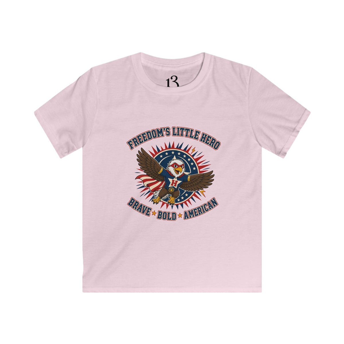 Front view of light pink kids T-shirt with a superhero eagle and “Freedom’s Little Hero — Brave, Bold, American” lettering.