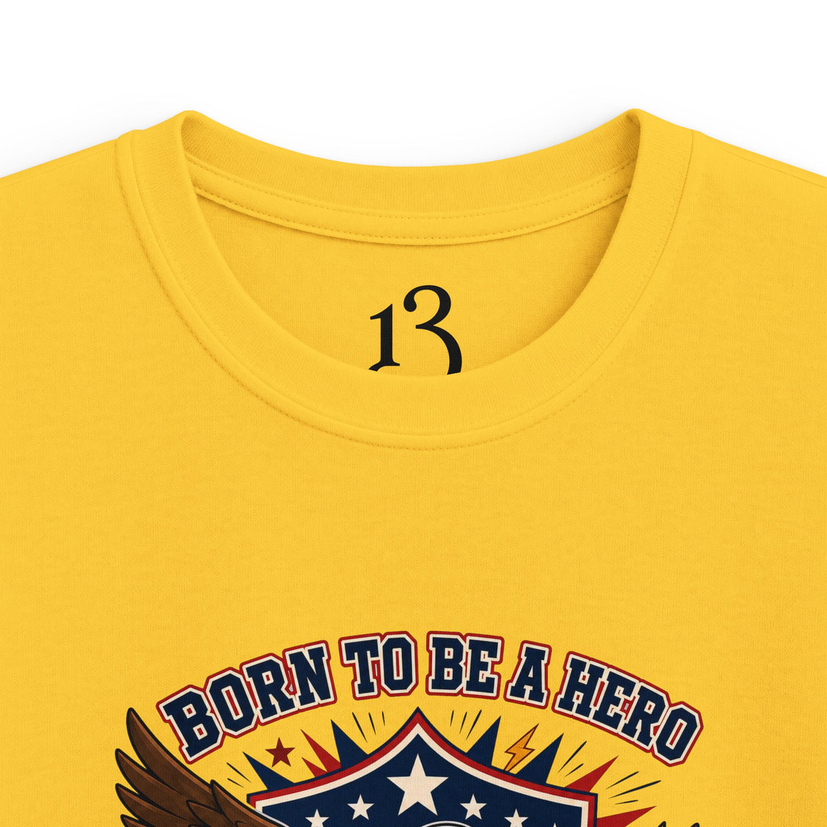 Close-up of yellow kids T-shirt neckline and “Born to Be a Hero” graphic.