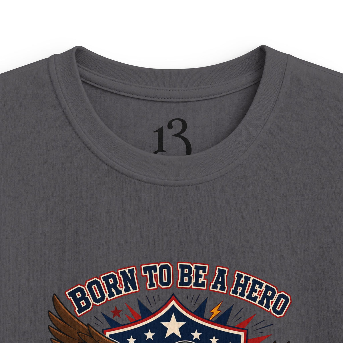 Close-up of charcoal kids T-shirt neckline and “Born to Be a Hero” graphic.